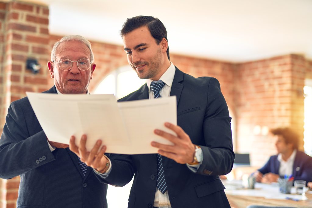 Two business workers working together. Speaking and reading documents standing at the office